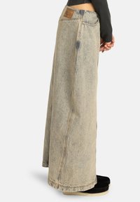 Gonna maxi in denim azzurro chiaro con lavaggio sbiadito. Caratterizzata da una vita alta, cuciture laterali e una toppa in pelle sulla parte posteriore. Design a lunghezza pavimento.