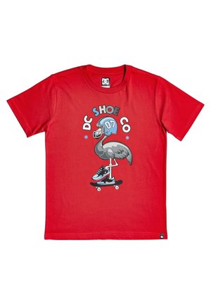 Maglietta rossa con un'immagine di un uccello che indossa un casco da football blu e sneakers, che va in skateboard, con la scritta "DC SHOE CO" sopra.