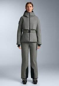 Sivá tvídová bunda s krátkym strihom, zipsovým zapínaním a opaskom v páse, skombinovaná s zodpovedajúcimi sivými nohavicami s čiernymi akcentmi.