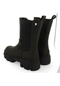 Botines negros hechos de material sintético liso con paneles elásticos en los lados, suela gruesa y un pequeño acento de logotipo metálico.