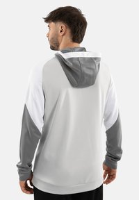 Felpa con cappuccio caratterizzata da una combinazione di colori grigia e bianca, maniche lunghe, texture liscia e accenti a contrasto sulle maniche e sul cappuccio.