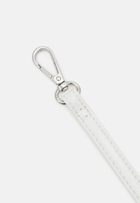 Vit läderrem med silvermetalldetaljer, med en klämma i änden och sömmar längs kanterna. Slät yta.