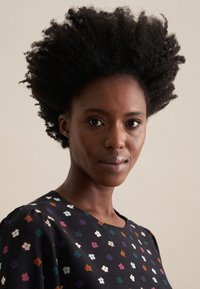 Blusa con motivo floreale nera, caratterizzata da vivaci disegni di fiori. Tessuto morbido, scollatura rotonda e maniche a sbuffo.