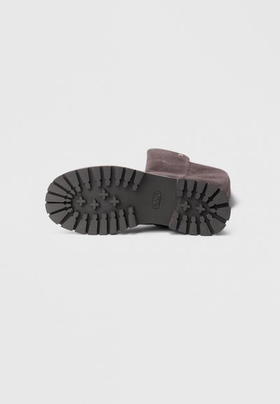 Semelle en caoutchouc noire avec des rainures profondes. Tige en suède gris foncé, présentant un design minimaliste et un petit détail doré, style bottine.