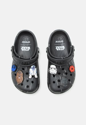 Sorte Crocs-sko med Star Wars-karaktervedhæng inklusive Chewbacca, R2-D2, Stormtrooper og Darth Vader på hver sko.