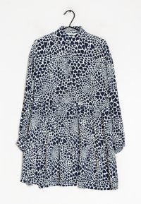 Camisa de manga larga con cuello tipo polo, que presenta un diseño abstracto de corazones en azul marino y blanco, hecha de una tela ligera.