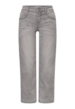 Persoon draagt lichtgrijze spijkerbroek, wit T-shirt en marineblauw jack met rits en knoopzakje, arm ontspannen naast het lichaam.