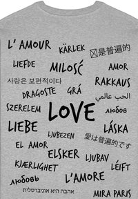 Felpa grigia con la parola "AMORE" in varie lingue, con una combinazione di caratteri e dimensioni, ben in evidenza tra altri elementi di testo.