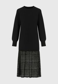 Robe noire avec un haut uni, des manches bouffantes longues et une jupe en dentelle texturée avec un motif en zigzag.