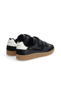 Black sneaker with velcro straps, leather and suede materials, gum rubber sole, and white heel accent. Branding in gold on the side.