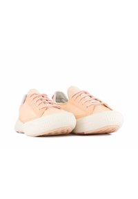 Baskets de couleur pêche avec une semelle blanche texturée, design à lacets et accents subtils. Tige en tissu lisse, avec un style minimaliste.
