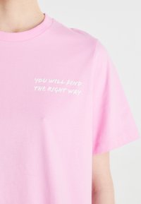 Camiseta de algodón de color rosa claro, con mangas cortas y cuello redondo. Texto "ENCONTRARÁS EL CAMINO CORRECTO" en cursiva blanca en el pecho.