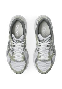 Scarpe sportive grigie e bianche con tomaia in rete, lacci spessi, colletto imbottito e dettagli riflettenti. Punta arrotondata e design minimalista.