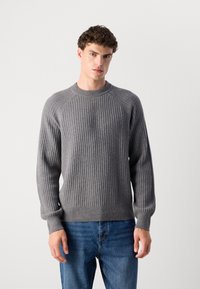 Gray ribbed knit sweater with raglan sleeves and a rounded neckline, featuring a textured finish and fitted cuffs, paired with blue jeans.