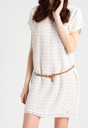 Robe à manches courtes en tissu crème clair avec un motif en diamants répétitif, cintrée à la taille par une ceinture beige.