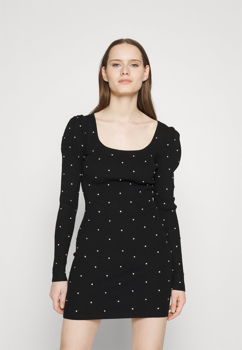 Schwarzes, geripptes Kleid mit langen Ärmeln und quadratischem Ausschnitt, verziert mit gleichmäßig verteilten weißen Perlen. Enganliegendes Design in kurzer Länge.