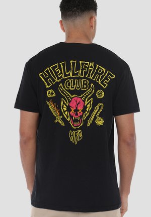 Schwarzes Baumwoll-T-Shirt mit buntem Grafikdruck eines Schädels, Hörnern und Waffen. Das Motiv enthält den Text „HELLFIRE CLUB“ in Gelb.