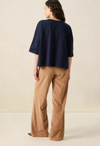 Navy oversized katoenen t-shirt met korte mouwen, gecombineerd met lichtbruine corduroy wijde broek, met een textuurstof en een ontspannen pasvorm.