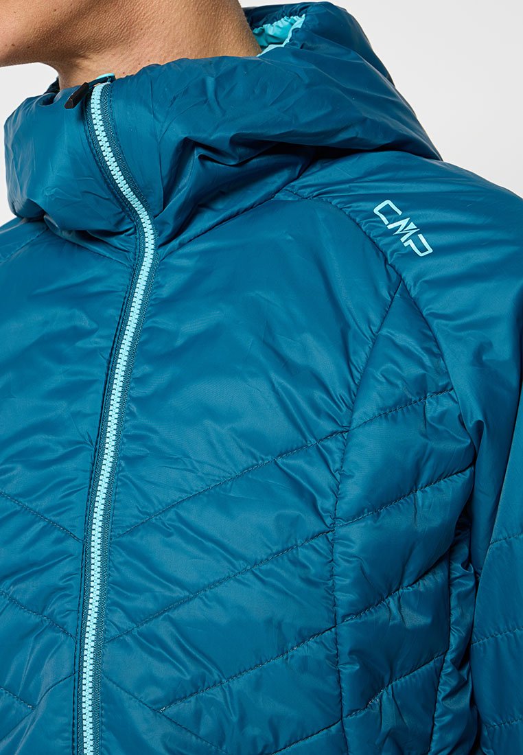 Giacca trapuntata color teal con chiusura a zip e cappuccio. Presenta una zip blu a contrasto e il logo CMP sulla spalla. Materiale liscio e leggero.