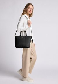 Schwarze Leder-Tote mit doppelten Obergriffen und einem abnehmbaren Schulterriemen, mit vertikalen Nähten und einem goldenen Logo-Akzent.