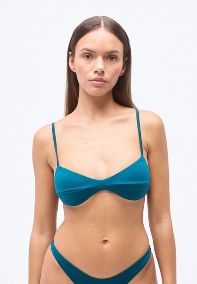 Haut de bikini turquoise à fines bretelles, présentant une texture lisse et mate avec une coupe large en triangle. Associé à un bas taille haute assorti.