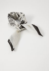 Eșarfă albă cu modele grafice negre, realizată dintr-un material ușor, cu un design înnodat și margini negre contrastante.