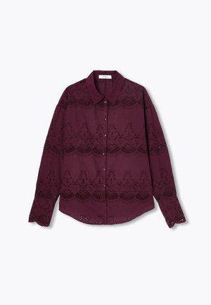 Chemise bordeaux à manches longues avec col, ornée de découpes en dentelleIntriquées et d'une fermeture à boutons, texture lisse et ourlet arrondi.