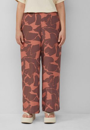 Wijdvallende broek met een roest- en bruine abstracte print, gemaakt van lichtgewicht stof. Gepaard met chunky beige plateau schoenen.