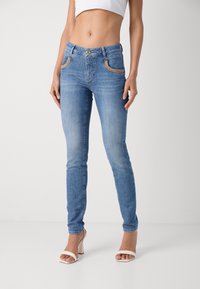 Oprijete jeans hlače v svetlo modrem denimu z gladko teksturo, ki vključujejo sprednje žepe s zlatimi detajli in prilagojenim dizajnom.
