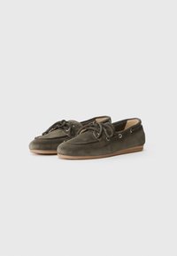Green suede boat shoes with a rounded toe, lace-up design, silver eyelets, and tan rubber sole. Smooth texture with minimal stitching details.