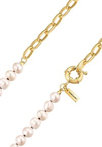 Gouden ketting met een onregelmatig gevormde witte parels en een ronde sluiting met een logo tag.