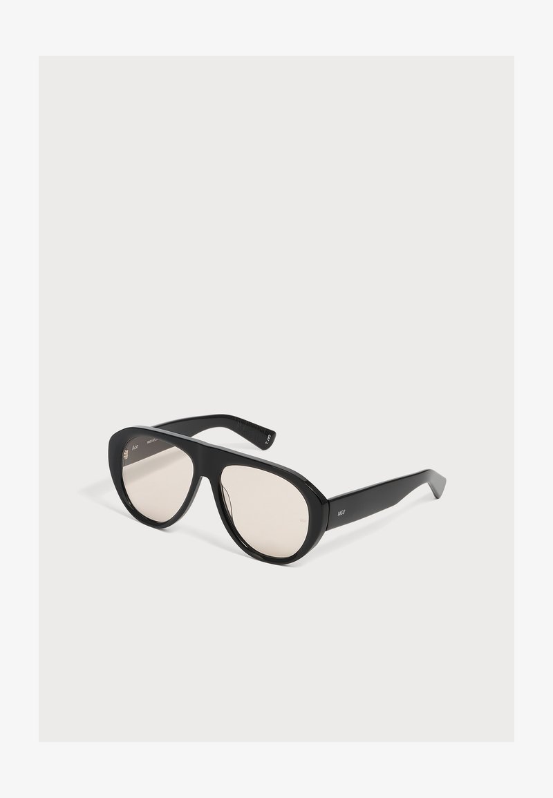 Lunettes de soleil aviateur noires surdimensionnées avec montures épaisses et verres légèrement teintés sur fond blanc.