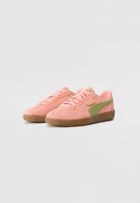 Baskets Puma avec tige en daim rose, accent vert sur le côté et semelle en caoutchouc gum. Présentent des lacets ronds et le logo sur le côté.