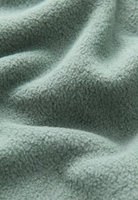 Blød, tekstureret fleece-stof i en dæmpet teal-farve, med en let fluffy overflade og subtile nuancer i farven.