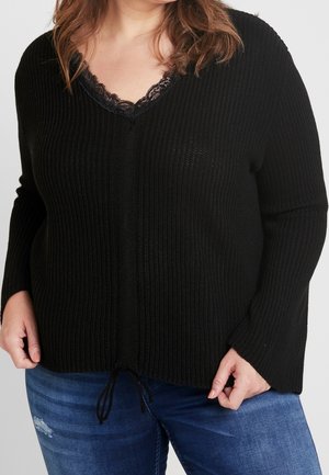 Sort strikket pullover med V-hals, der har en blondekant og justerbar snøring i kanten. Lange ærmer med ribbet tekstur.