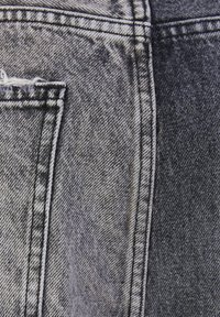 Gray denim fabric with a textured surface, featuring a visible pocket and contrasting stitching along the seams and edges.