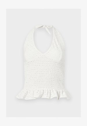 Bílý krátký top s halter výstřihem, našitým žabičkováním, děrovanými detaily a volánkovým lemem na jednoduchém pozadí.