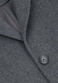 Szary płaszcz wełniany o eleganckim kroju, z wyciętym kołnierzem, zapięciem na guziki i gładką podszewką widoczną pod tkaniną.