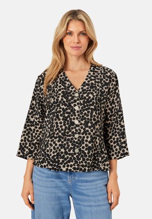 Blusa nera a pois con scollatura a V, maniche a tre quarti e bottoni frontali. Il tessuto ha una finitura testurizzata su uno sfondo chiaro.