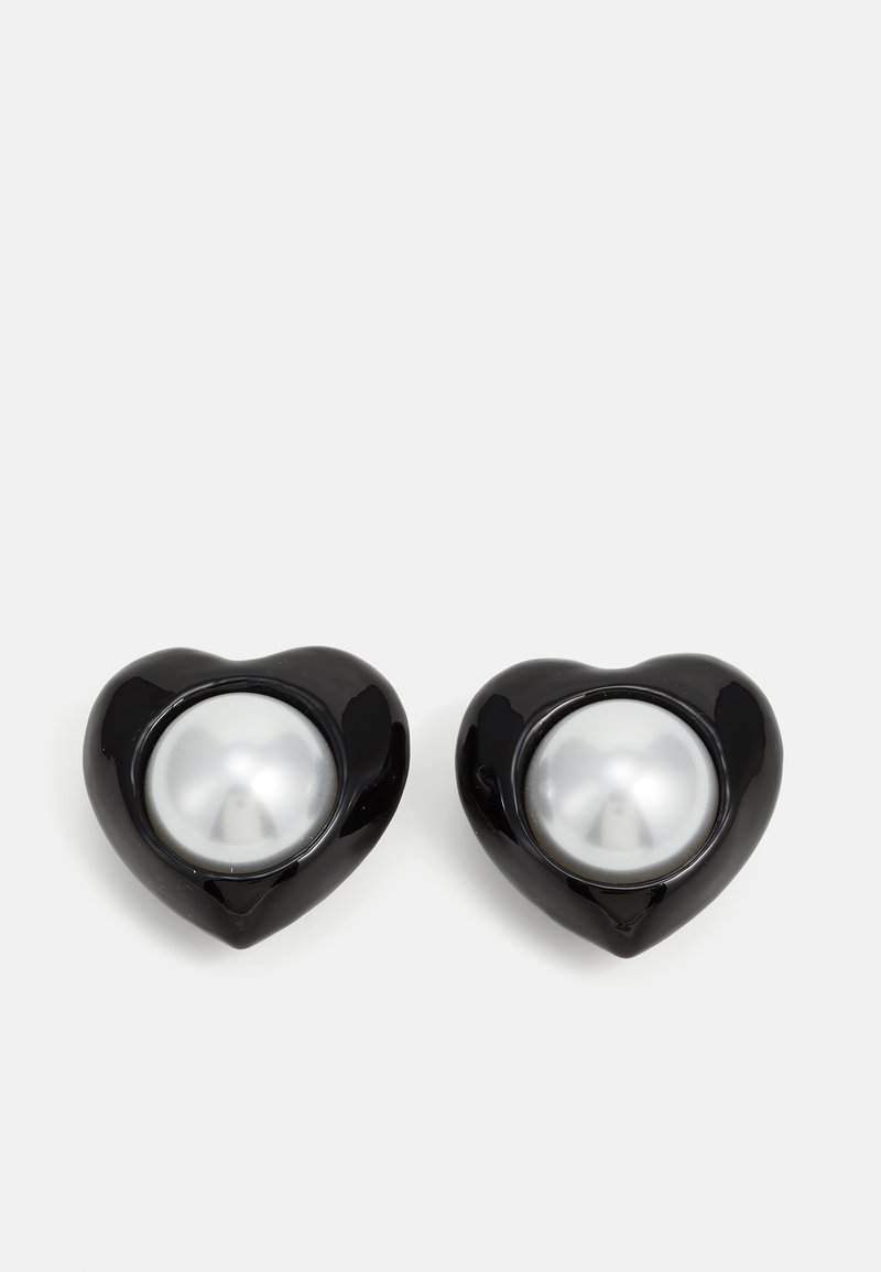 Schwarze herzförmige Ohrringe mit glänzender Oberfläche, die ein auffälliges silbernes Perlenzentrum aufweisen. Glatte Textur mit abgerundeten Kanten.