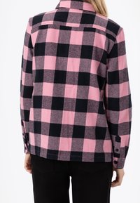 Camicia flanella con colletto, in un motivo a scacchi rosa e nero, con maniche lunghe e polsini abbottonati. Tessuto morbido e vestibilità ampia.
