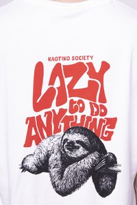 Maglietta bianca in cotone con un'illustrazione nera di un bradipo e testo rosso che recita: "LAZY to DO ANYTHING." Design grafico semplice.