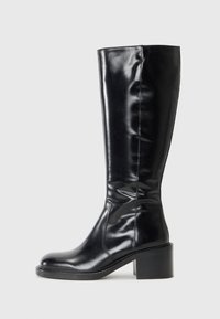 Μαύρες μπότες μέχρι το γόνατο με γυαλιστερή δερμάτινη επιφάνεια, στρογγυλή μύτη και τετράγωνη φτέρνα. Λείο υλικό με ορατές ραφές.