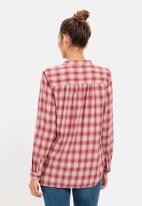 Chemise en flanelle à carreaux rouges et crème avec manches longues, poignets à boutons et un détail de yoke au dos. Texture douce, coupe décontractée.