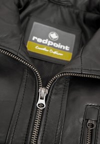 Schwarze Lederjacke mit silbernem Reißverschluss, strukturiertem Material und einem Innenetikett mit der Aufschrift "redpoint." Verfügt über eine Brusttasche mit Reißverschluss.