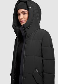 Black puffer jacket with a high collar and adjustable hood, featuring a zip closure and side pockets. Smooth fabric with quilted pattern.