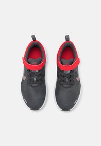 Scarpe da ginnastica nere e grigie con un colletto rosso e una fascia. Presentano una parte superiore testurizzata, lacci e una suola bianca con un'etichetta di trazione a motivo.