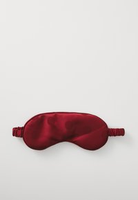 Masca pentru ochi din satin roșu cu o textură netedă, având un model de buline roșii mai închise și o curea elastică de fiecare parte.