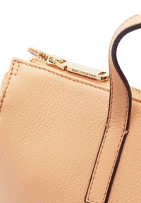 Sac à main en cuir tan avec une finition texturée, matériel de fermeture éclair doré et une courte poignée. Marque embossée près de la fermeture éclair.