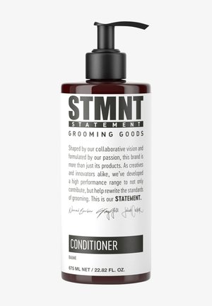 Flacon pompe brun foncé étiqueté STMNT Statement Grooming Goods après-shampoing contenant 675 ml de liquide et texte descriptif de la marque sur fond blanc.